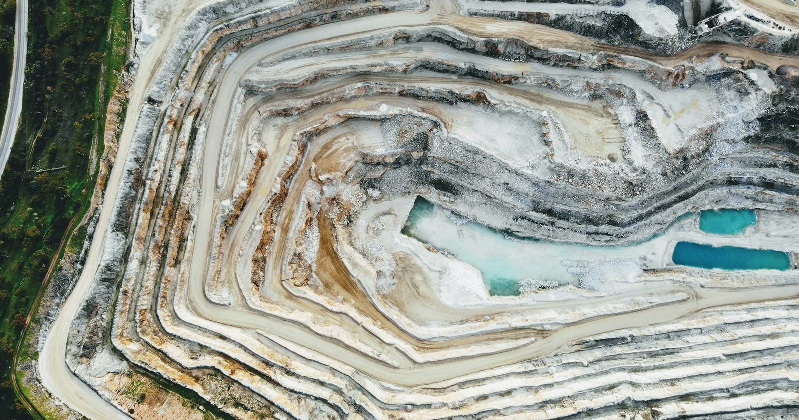 Aerial view of terraced open-pit mine with turquoise water pools