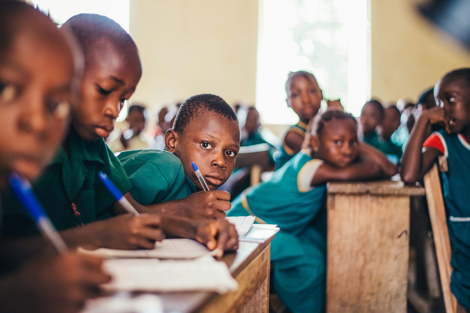 Children writing in exercise books in a classroom