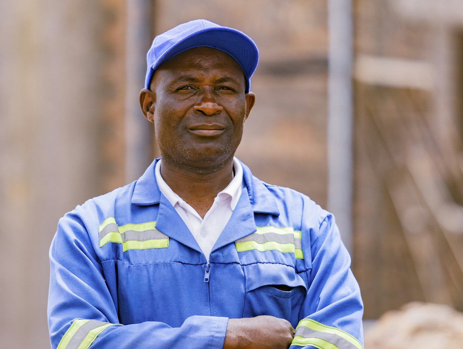 Plant worker in blue uniform and cap, arms folded, looking at the camera