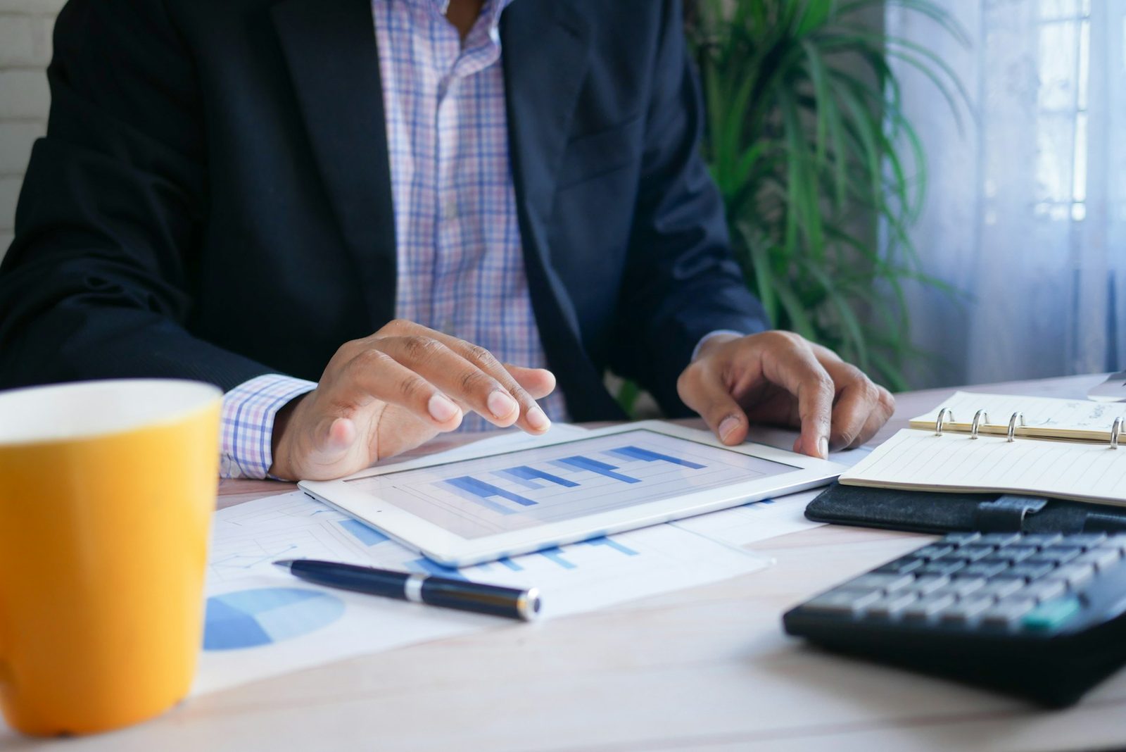 Finance professional reviewing charts on a tablet beside calculator and reports