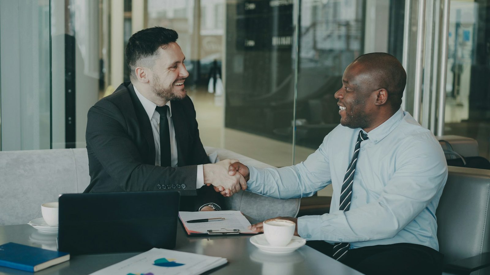 African and international professionals shake hands across a meeting table with documents