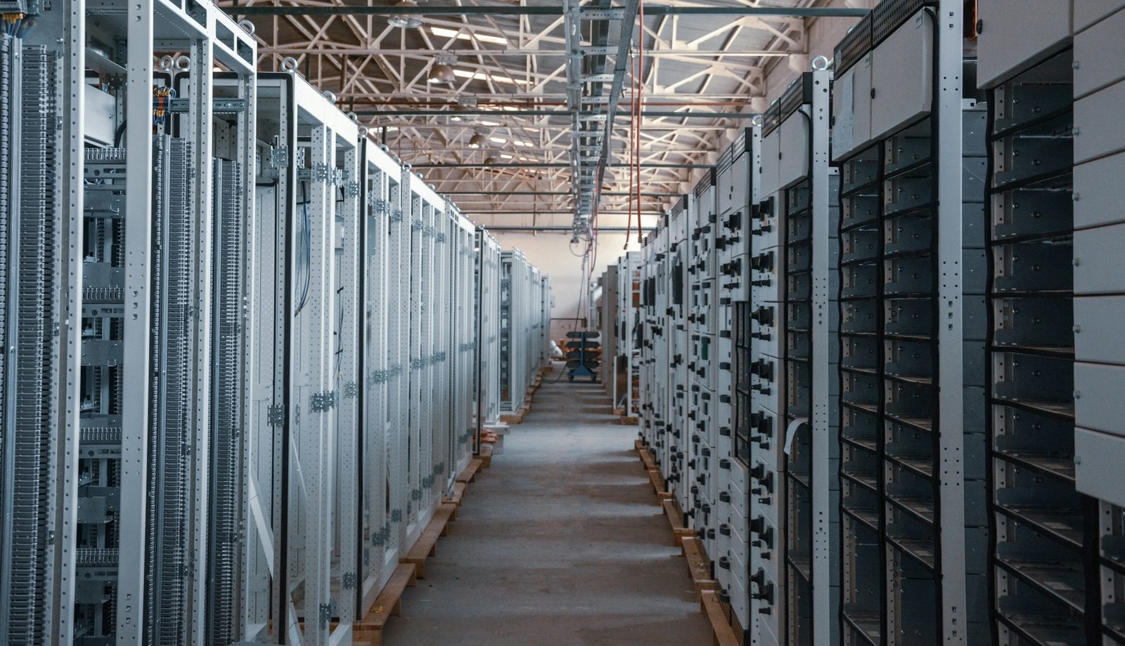Bright aisle between rows of grey server and equipment racks in a data hall