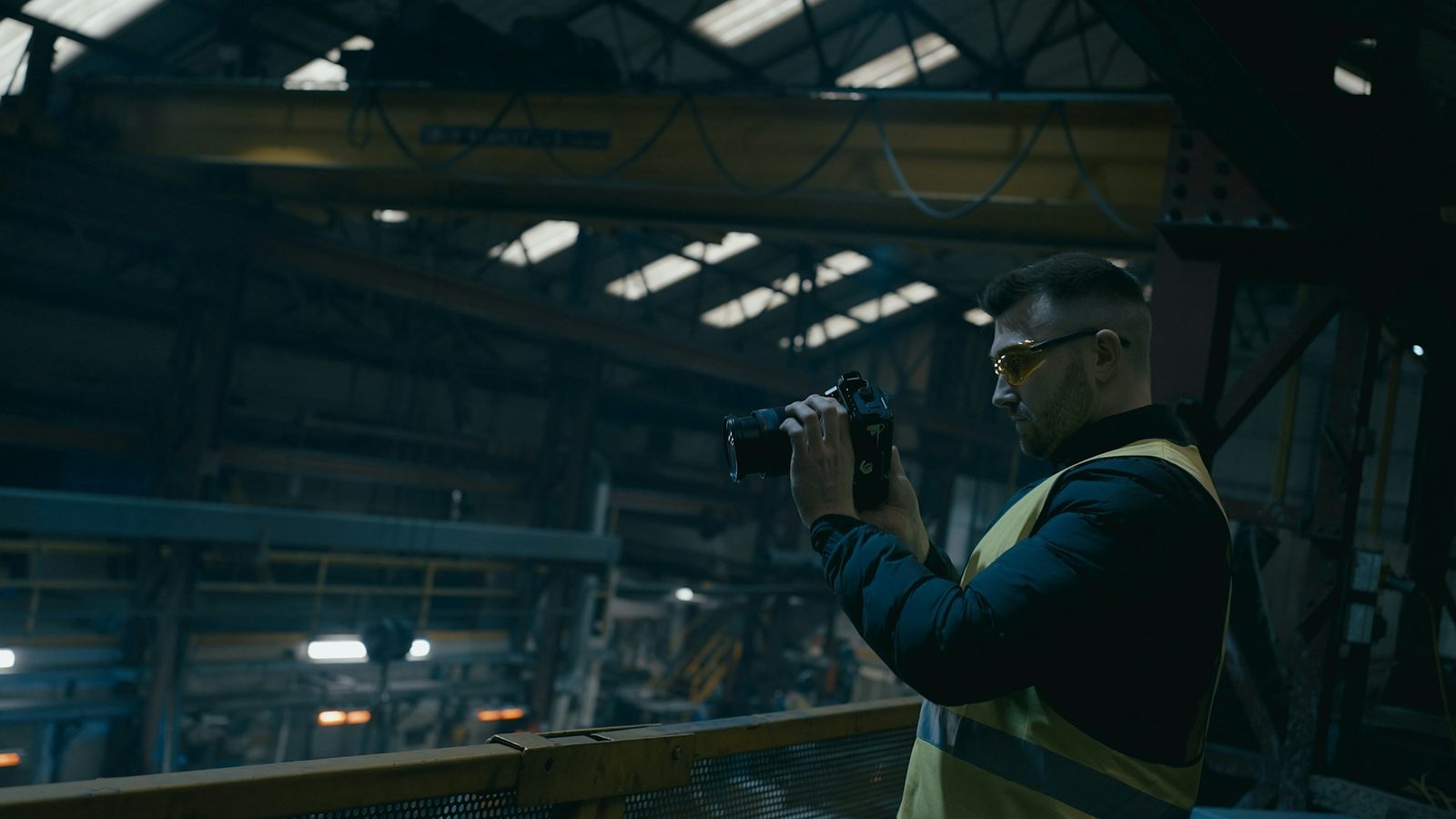 Inspector in a safety vest photographing equipment inside an industrial plant